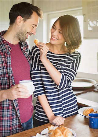 simsearch:6113-06908484,k - Girlfriend feeding boyfriend croissant in kitchen Foto de stock - Sin royalties Premium, Código: 6113-08393713