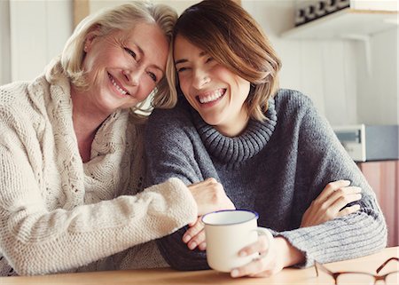 Laughing mother and daughter in sweaters hugging and drinking coffee Photographie de stock - Premium Libres de Droits, Code: 6113-08393733