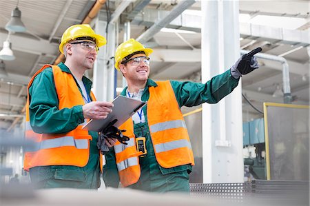 simsearch:6113-08393862,k - Workers in protective workwear talking with clipboard in factory Photographie de stock - Premium Libres de Droits, Code: 6113-08393861