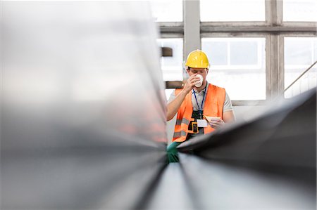 Worker in protective workwear drinking coffee in factory Foto de stock - Sin royalties Premium, Código: 6113-08393872