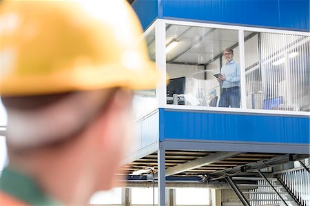 powerful male blue collar - Worker looking up at businessman in factory office Stock Photo - Premium Royalty-Free, Code: 6113-08393884