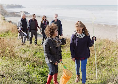 Multi-generation family with nets walking on sunny grass beach path Stock Photo - Premium Royalty-Free, Code: 6113-08393805