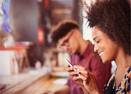 dominican black people - Smiling woman texting with cell phone Stock Photo - Premium Royalty-Free, Code: 6113-08321098