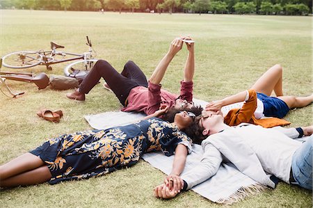 Friends relaxing and taking selfie in circle on blanket in park Foto de stock - Sin royalties Premium, Código: 6113-08321190