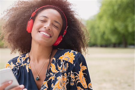 simsearch:6113-08321133,k - Enthusiastic woman listening to music with headphones and mp3 player in park Stock Photo - Premium Royalty-Free, Code: 6113-08321130