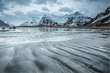 Snow covered mountains behind cold beach, Skagsanden Beach, Lofoten Islands, Norway Photographie de stock - Premium Libres de Droits, Code: 6113-08321274