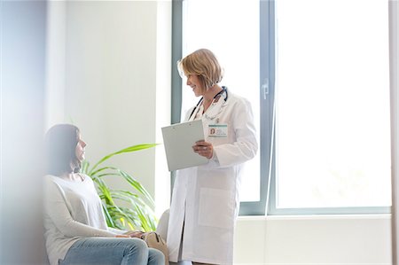 simsearch:6113-08321321,k - Doctor with medical record talking to patient in waiting room Photographie de stock - Premium Libres de Droits, Code: 6113-08321288