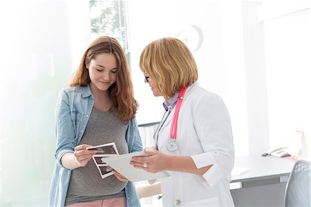 pregnant and doctor - Doctor and pregnant teenage patient viewing ultrasound x-rays in doctor's office Foto de stock - Sin royalties Premium, Código: 6113-08321308