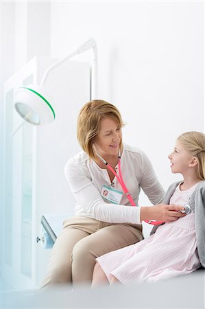 Pediatrician using stethoscope on girl patient in examination room Photographie de stock - Premium Libres de Droits, Code: 6113-08321314