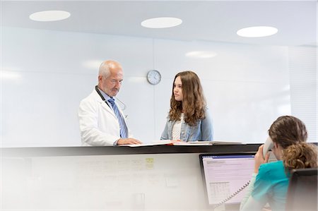 simsearch:6113-08321288,k - Doctor and teenage patient discussing medical record at nurses station Stock Photo - Premium Royalty-Free, Code: 6113-08321324