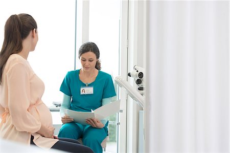 simsearch:6113-08321288,k - Nurse and pregnant patient reviewing medical chart in examination room Stock Photo - Premium Royalty-Free, Code: 6113-08321334