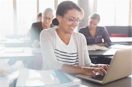 simsearch:6113-08321448,k - Smiling woman typing at laptop in adult education classroom Fotografie stock - Premium Royalty-Free, Codice: 6113-08321458