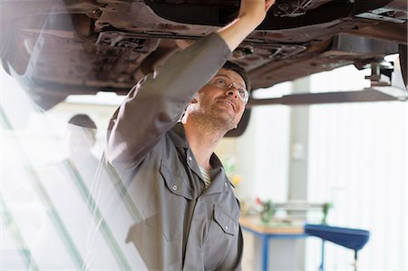 Mechanic working under car in auto repair shop Photographie de stock - Premium Libres de Droits, Code: 6113-08321475