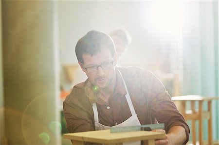 simsearch:6113-08321469,k - Focused carpenter measuring wood in workshop Stock Photo - Premium Royalty-Free, Code: 6113-08321483