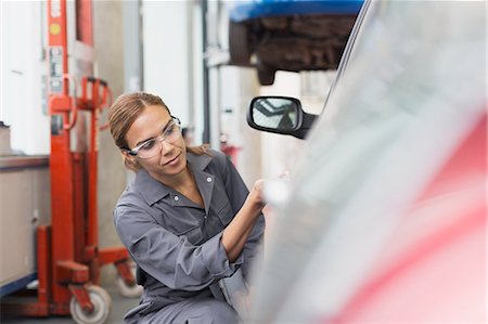 simsearch:6113-08321353,k - Female mechanic examining car in auto repair shop Foto de stock - Sin royalties Premium, Código: 6113-08321411