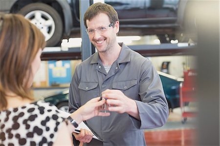 simsearch:6113-08321418,k - Mechanic taking keys from woman in auto repair shop Foto de stock - Sin royalties Premium, Código: 6113-08321415