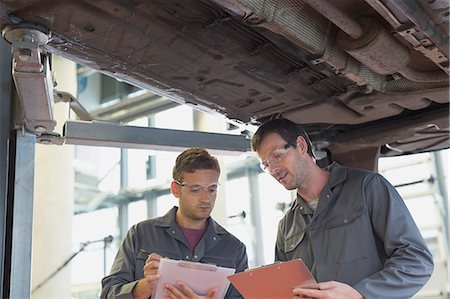 simsearch:6113-08184348,k - Mechanics with clipboards talking under car in auto repair shop Photographie de stock - Premium Libres de Droits, Code: 6113-08321418