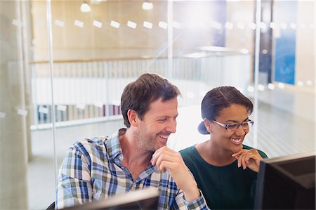 research talk - Smiling businessman and businesswoman working at computer in office Stock Photo - Premium Royalty-Free, Code: 6113-08321425