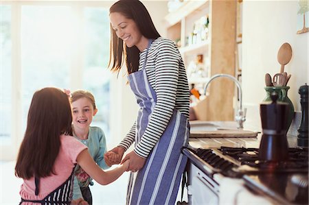 Mother and daughters holding hands in kitchen Foto de stock - Sin royalties Premium, Código: 6113-08321593