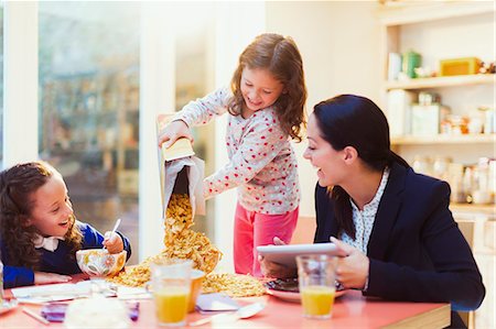 Girl pouring abundance of cereal at breakfast table Stock Photo - Premium Royalty-Free, Code: 6113-08321595