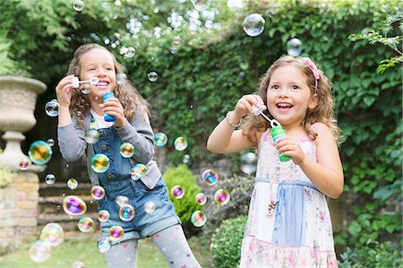 Carefree girls blowing bubbles in backyard Stock Photo - Premium Royalty-Free, Code: 6113-08321598