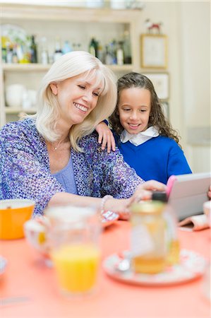 Grandmother and granddaughter using digital tablet at breakfast table Foto de stock - Sin royalties Premium, Código: 6113-08321599