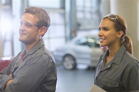 simsearch:6113-08321418,k - Smiling mechanics looking away in auto repair shop Foto de stock - Sin royalties Premium, Código: 6113-08321507