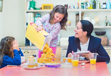 Playful girl pouring abundance of cereal onto breakfast table Foto de stock - Sin royalties Premium, Código: 6113-08321645