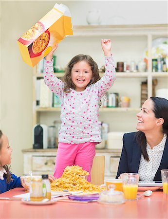 food box - Portrait enthusiastic girl cheering with cereal box at breakfast table Stock Photo - Premium Royalty-Free, Code: 6113-08321605