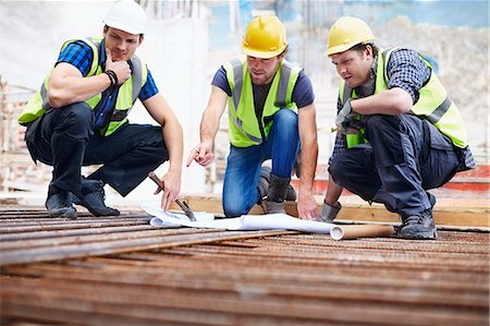 squat - Construction workers and engineer reviewing blueprints at construction site Stock Photo - Premium Royalty-Free, Code: 6113-08321762
