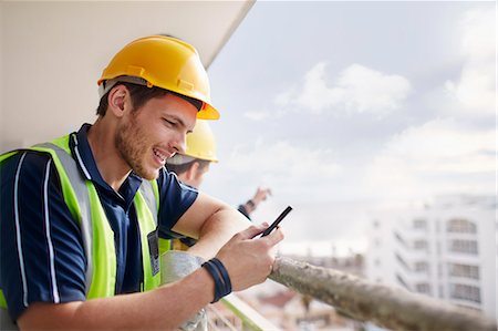 Construction worker texting at highrise construction site Stock Photo - Premium Royalty-Free, Code: 6113-08321734