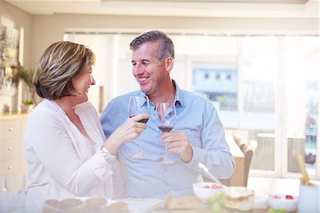 simsearch:6113-07790692,k - Smiling couple toasting red wine glasses in kitchen Foto de stock - Sin royalties Premium, Código: 6113-08424157