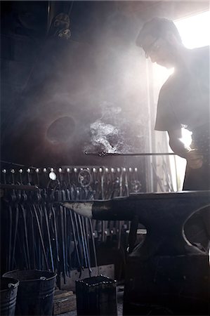 rustic workshop - Blacksmith holding steaming wrought iron over anvil in forge Stock Photo - Premium Royalty-Free, Code: 6113-08424278