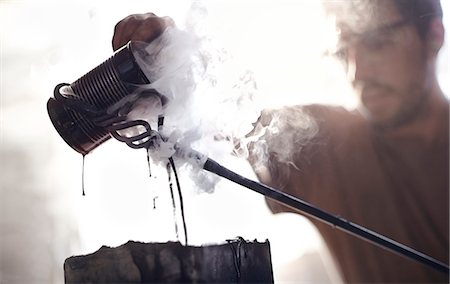 simsearch:6113-08424286,k - Blacksmith pouring steaming liquid over wrought iron Stock Photo - Premium Royalty-Free, Code: 6113-08424280