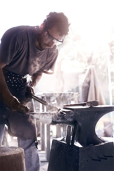 Blacksmith shaping iron over anvil in forge Stock Photo - Premium Royalty-Free, Image code: 6113-08424285