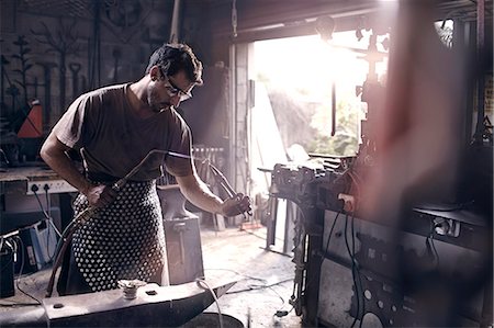 Blacksmith using blow torch in forge Foto de stock - Sin royalties Premium, Código: 6113-08424305