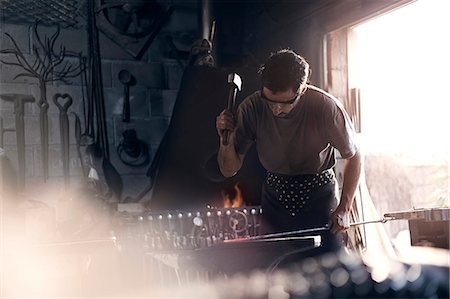 Blacksmith forging iron at anvil in forge Stock Photo - Premium Royalty-Free, Code: 6113-08424311