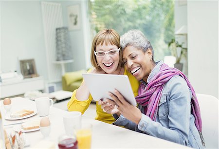 Laughing mature women sharing digital tablet at breakfast table Foto de stock - Sin royalties Premium, Código: 6113-08550041