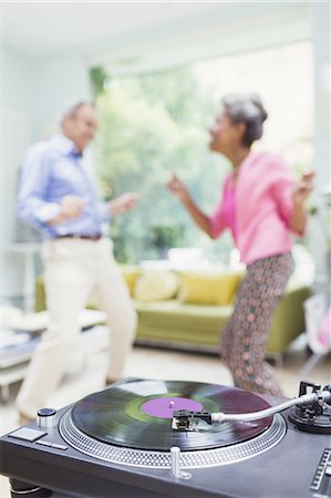 retro person listening music - Playful nature couple dancing in living room behind record player Stock Photo - Premium Royalty-Free, Code: 6113-08550042