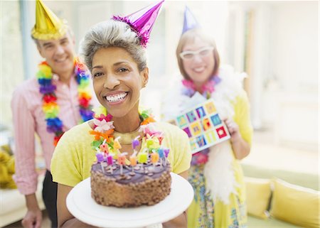 simsearch:6113-08549933,k - Portrait smiling mature woman holding chocolate birthday cake with friends in background Stock Photo - Premium Royalty-Free, Code: 6113-08550052