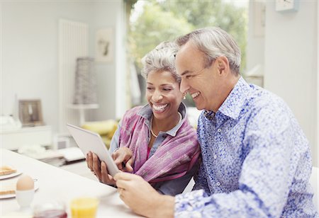 simsearch:6113-09157606,k - Smiling mature couple sharing digital tablet at breakfast table Stock Photo - Premium Royalty-Free, Code: 6113-08550060