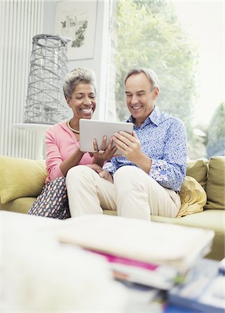 simsearch:6113-07648795,k - Smiling mature couple sharing digital tablet on living room sofa Foto de stock - Royalty Free Premium, Número: 6113-08550079