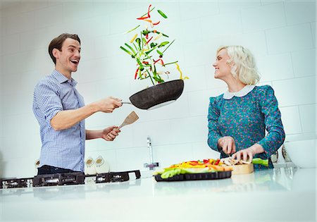 simsearch:6113-06908515,k - Surprised couple cooking flipping vegetables in skillet in kitchen Stock Photo - Premium Royalty-Free, Code: 6113-08550093