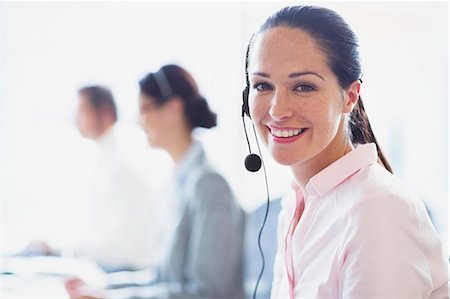 Portrait of smiling businesswoman talking on the phone with headset Stock Photo - Premium Royalty-Free, Code: 6113-08550020