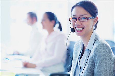 Portrait of smiling businesswoman talking on the phone with headset Stock Photo - Premium Royalty-Free, Code: 6113-08550021