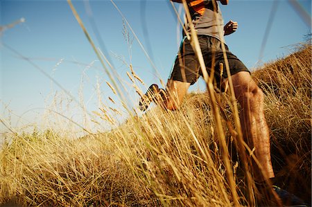 runner from below - Man running through tall grass on sunny trail Stock Photo - Premium Royalty-Free, Code: 6113-08550157
