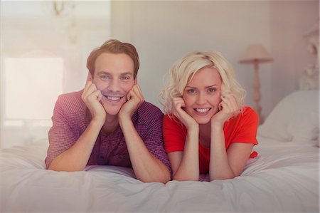 simsearch:6113-07731678,k - Portrait smiling couple with head in hands on bed Photographie de stock - Premium Libres de Droits, Code: 6113-08550108