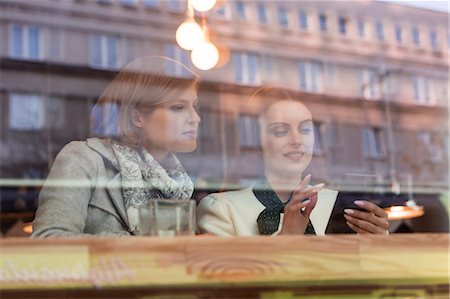 simsearch:614-08081431,k - Businesswomen using cell phone at cafe window Stock Photo - Premium Royalty-Free, Code: 6113-08550128