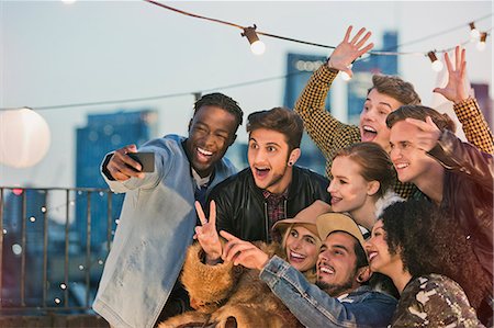 Enthusiastic young adult friends cheering and taking selfie at rooftop party Foto de stock - Sin royalties Premium, Código: 6113-08568544
