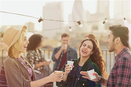 Young adult friends laughing and drinking at rooftop party Photographie de stock - Premium Libres de Droits, Code: 6113-08568561